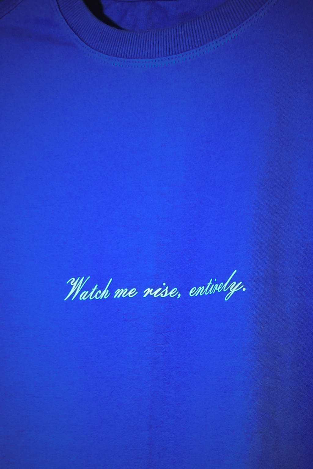 Blue tshirt with white text 'Watch me rise, entirely.'