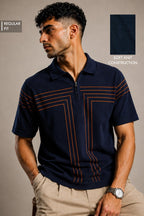 A man wearing a navy blue short-sleeve polo shirt with orange geometric stripe details on the chest, paired with khaki pants. The image includes text overlays indicating 'REGULAR FIT' and a swatch showing 'SOFT KNOT CONSTRUCTION'.