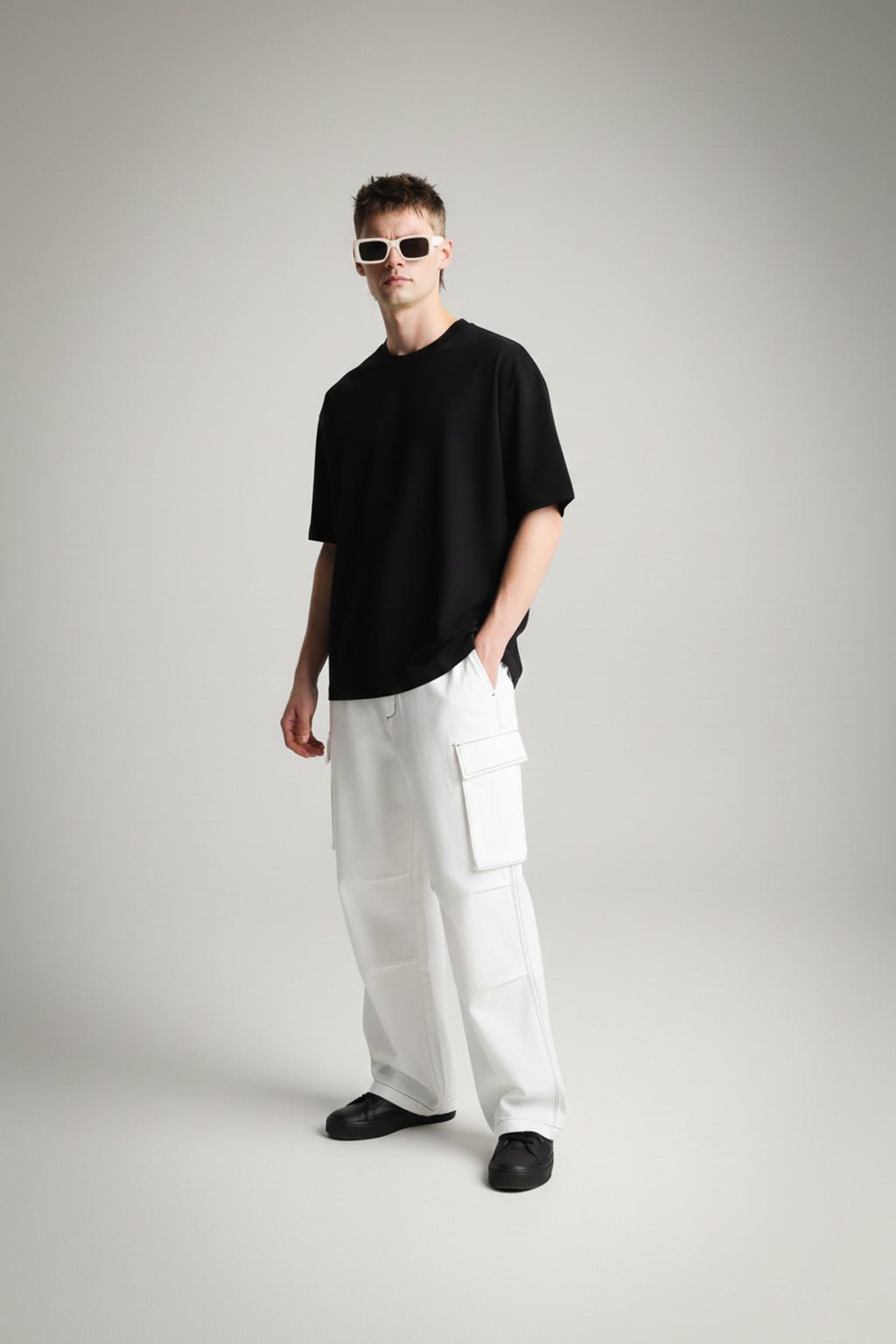 Person wearing a solid black t-shirt and white pants on a gray background