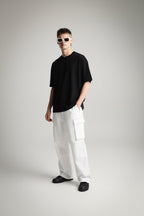 Person wearing a solid black t-shirt and white pants on a gray background