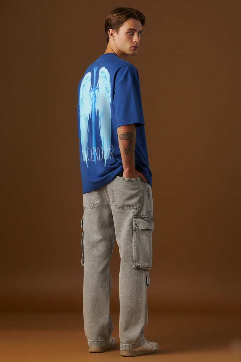 Male model wearing blue oversized t-shirt with angel wings and sword graphic back print full body view