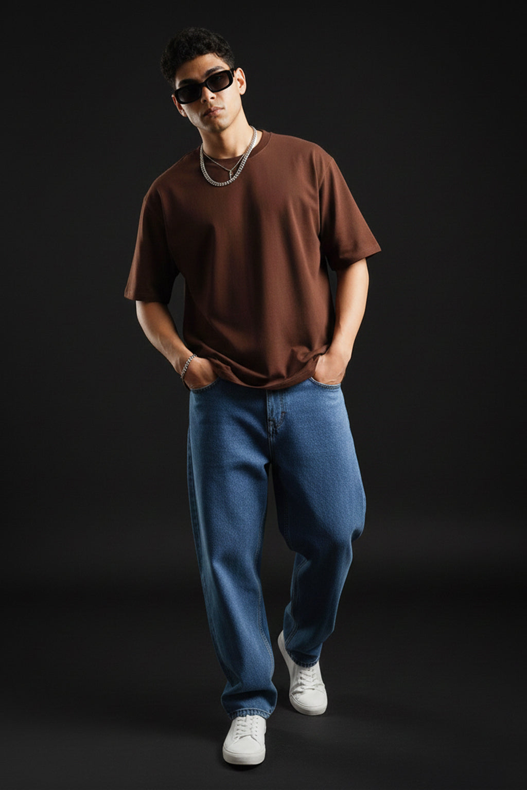 Person wearing a brown t-shirt, blue jeans, and sunglasses on a black background