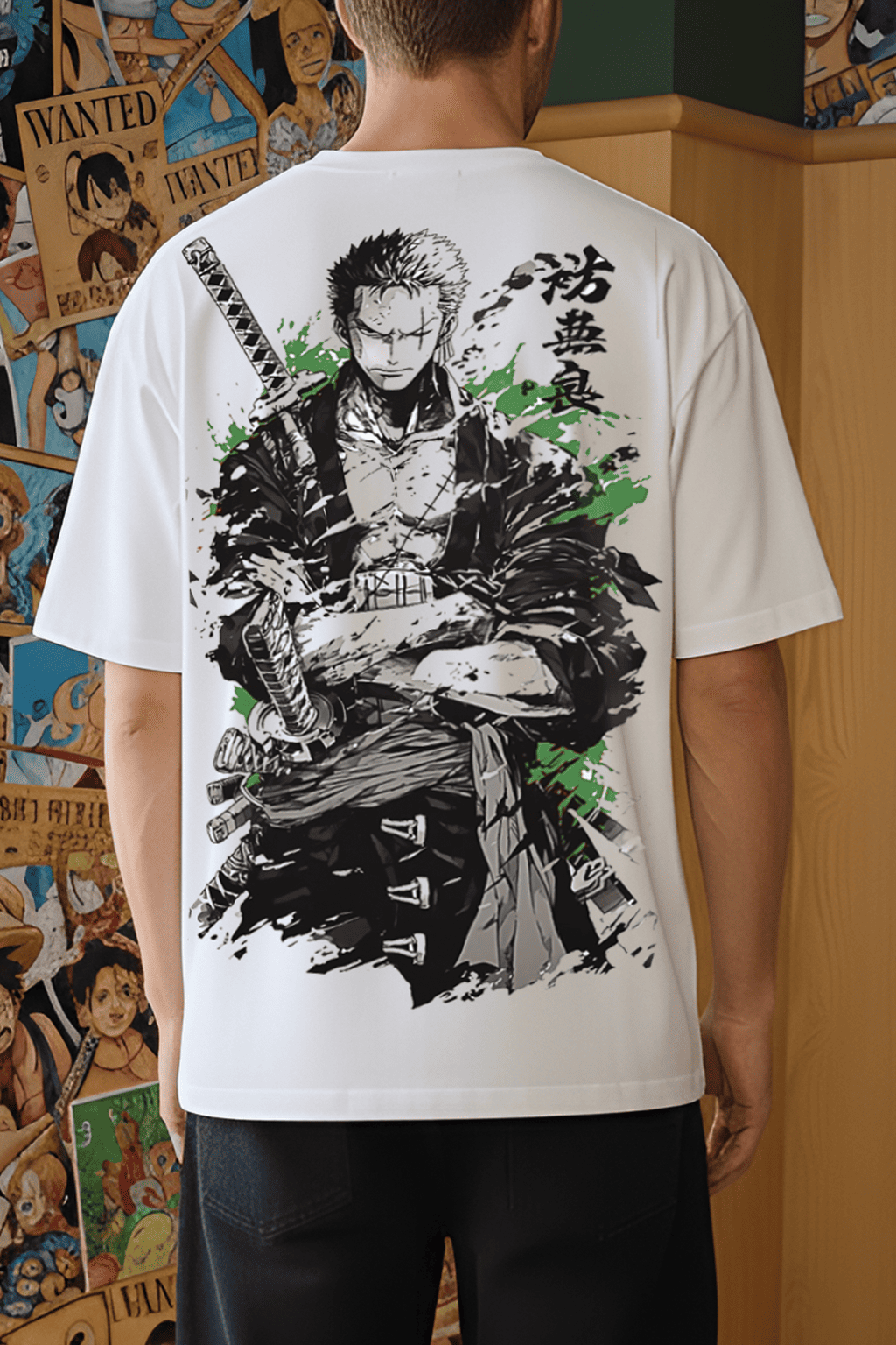 Person wearing a white t-shirt with a black and green graphic design on the back, standing in front of a wall with comic book posters.