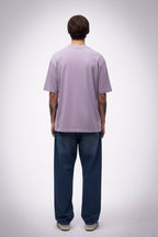 Person wearing a light purple solid t-shirt and blue pants on a white background