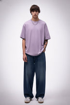 Person wearing a solid light purple t-shirt and blue jeans on a white background