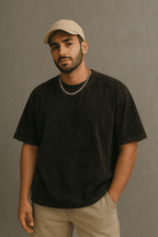 Man wearing a black acid wash oversized French terry t-shirt, 240 GSM heavyweight tee styled with a beige cap