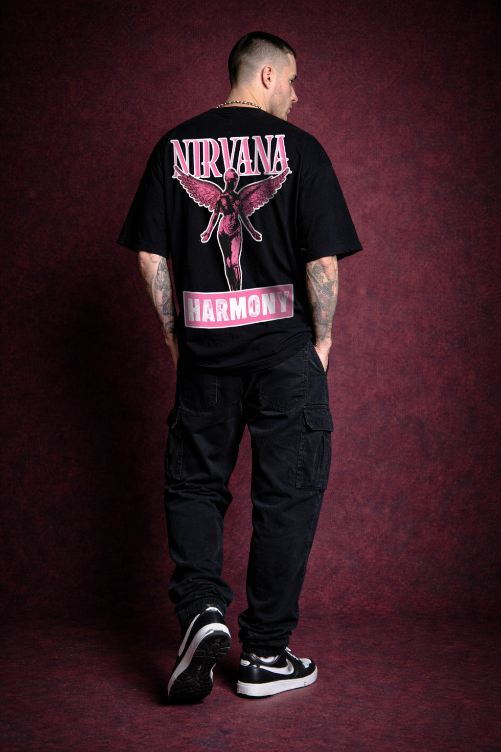 Person wearing a black Nirvana t-shirt with pink design on a dark red background