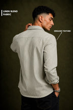 A man shown from the back wearing a light beige and white vertically striped linen shirt, with text overlays highlighting the fabric's organic texture.