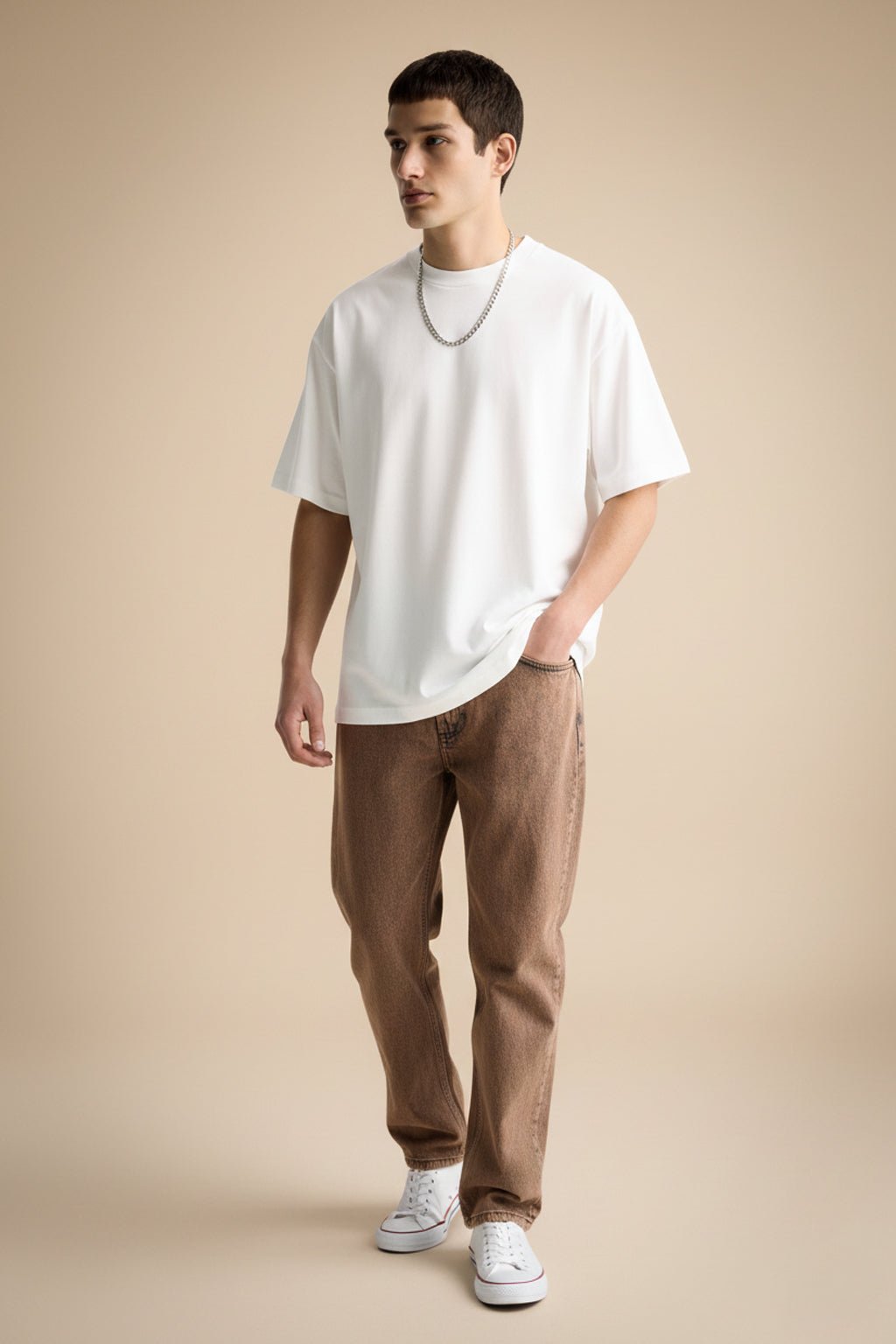 Man wearing a white t-shirt and brown pants on a beige background