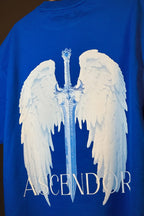 Blue t-shirt with white angel wings and a sword graphic on a dark background