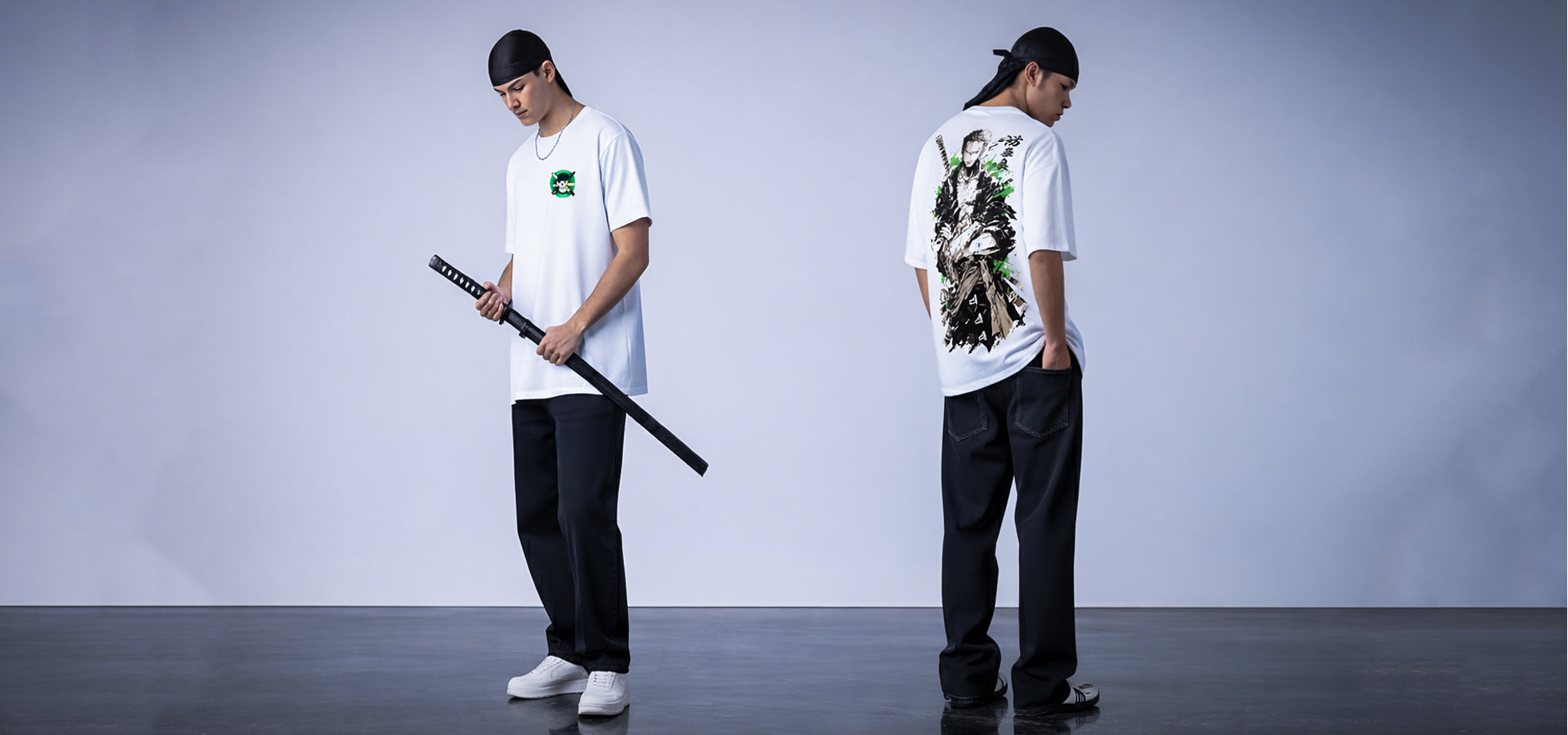 Two people wearing white t-shirts with graphic designs, one holding a sword, on a plain background.